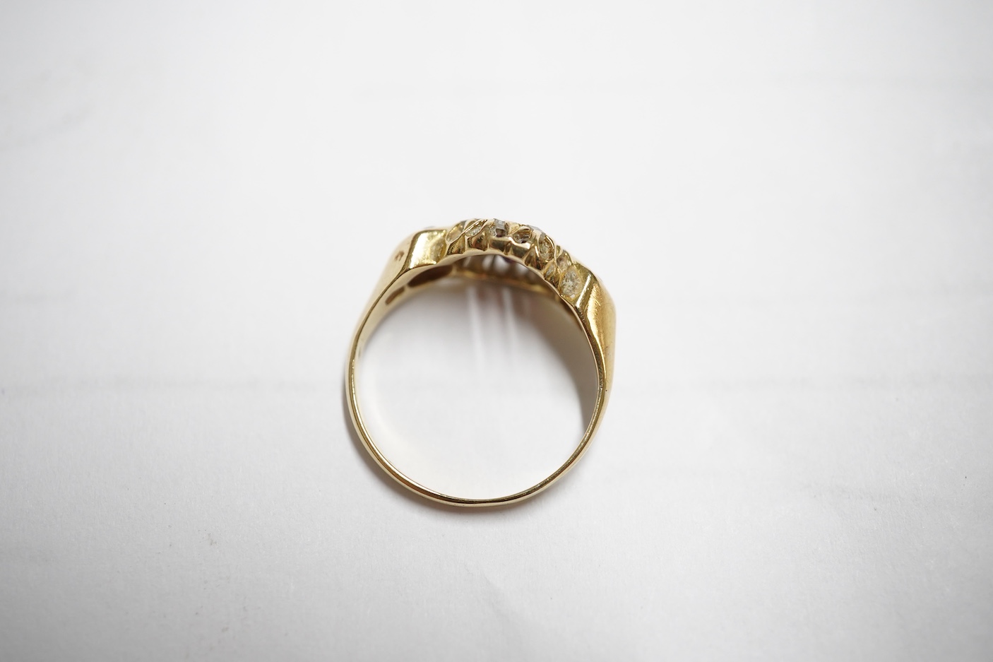 An early 20th century yellow metal and three stone ruby set ring, the centre stone bordered with rose cut diamonds, size H/I, gross weight 2.8 grams.